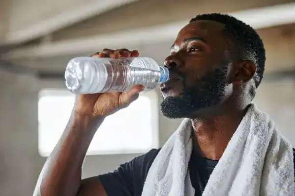 Hydration: The Secret Ingredient for a Toned Stomach and Enhanced Fitness 1 Image of man drinking water to improve hydration Maplehurst after work out.